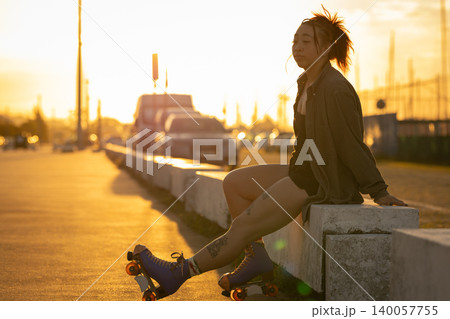 Young woman relaxing with roller skates during golden hour 140057755