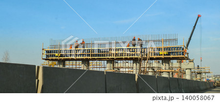 Construction workers standing on a half-built concrete bridge structure with rebar and formwork, actively working on new infrastructure on a sunny day. Construction workers standing on a half-built concrete bridge structure with rebar and formwork, actively working on new infrastructure on a sunny day. 140058067