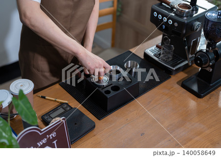 Young barista making coffee, coffee preparation service concept. 140058649