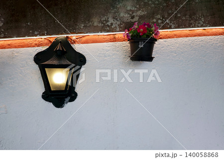 Vintage black street lamp and small flower pot on a white wall in Sintra, Portugal Vintage black street lamp and small flower pot on a white wall in Sintra, Portugal 140058868
