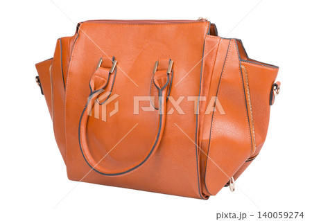 Ginger brown leather handbag with side zippers isolated on white background. Side view of a modern female trapeze tote bag with top handles. 140059274
