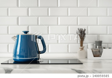 Blue electric kettle in modern kitchen interior with white tile backsplash Blue electric kettle in modern kitchen interior with white tile backsplash 140059385