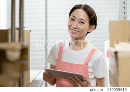 倉庫で働くミドルの女性作業員 倉庫で働くミドルの女性作業員 140059619