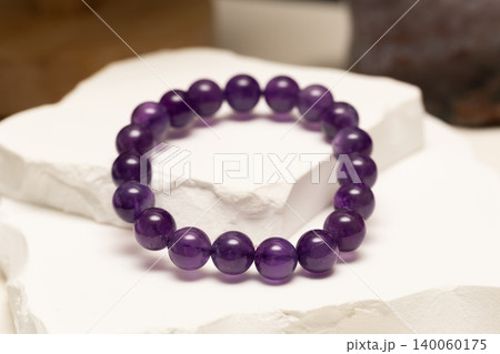 Natural stone bracelet made of amethyst on white surface Natural stone bracelet made of amethyst on white surface 140060175