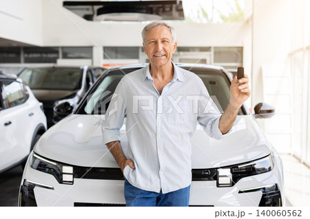 Happy mature customer standing in front of new SUV, holding car key Happy mature customer standing in front of new SUV, holding car key 140060562