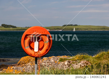 Red Lifebuoy Installation at a Seafront Location with Selective Focus Island Behind Red Lifebuoy Installation at a Seafront Location with Selective Focus Island Behind 140061241