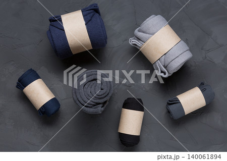 Set of men's cotton socks rolled in eco craft paper packaging on dark concrete background, top view mock up Set of men's cotton socks rolled in eco craft paper packaging on dark concrete background, top view mock up 140061894