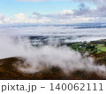 The foreground is a brown, grassy hillside with wisps of fog creeping down from above. 140062111