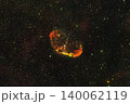 An astrophotography image capturing the Crescent Nebula, NGC 6888, glowing with orange and red gas clouds surrounded by countless stars in the deep space background. 140062119