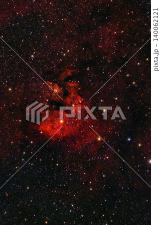 A spectacular cosmic display unfolds in the night sky, with a glowing red emission nebula, intricate dark dust lanes and countless brilliant stars. 140062121