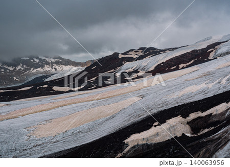 Aerial above cracked epic glacier Elbrus Caucasus mountain. Snow-capped highest peaks in fog clouds, glacier melting. 140063956