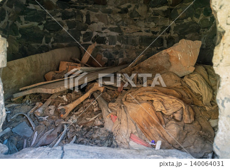 Interior view of an ancient Dargavs burial crypt, revealing human skeletal remains and deteriorated textiles 140064031