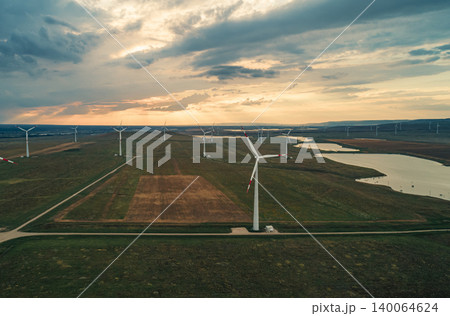 Arial view of a wind turbines generate clean energy against a stunning sunset in the countryside 140064624