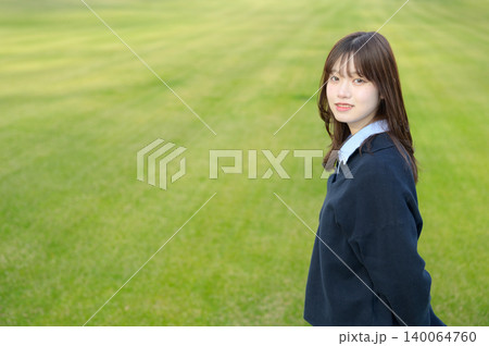 芝生の上で振り返って微笑む日本人女子高生 140064760