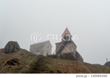 Misty hill contains ancient stone chapels. Holy Trinity Church in Gergeti. Georgia. Misty hill contains ancient stone chapels. Holy Trinity Church in Gergeti. Georgia. 140066360