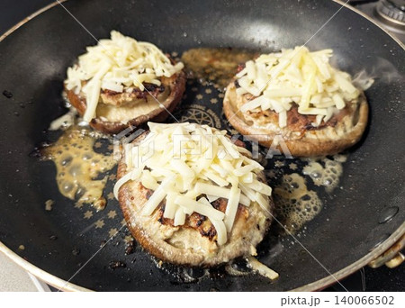 フライパンで調理中のとろけるチーズをのせたしいたけの肉詰め 140066502