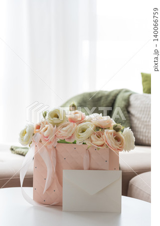 Ranunculus Bouquet with Gift Bag and Envelope in Cozy Living Room Ranunculus Bouquet with Gift Bag and Envelope in Cozy Living Room 140066759