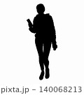 A woman stands and holds a phone and a cup of coffee in her hands 140068213
