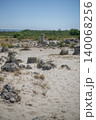 Large boulders on the sand surrounded by bushes 140068256