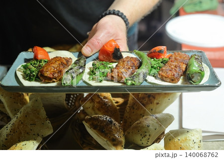A plate with a shish and adana kebab in the hands of a cook closeup 140068762