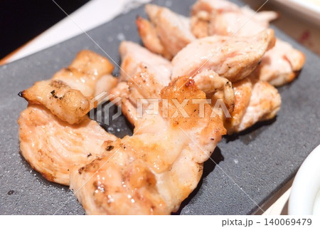 黒い皿に盛られた香ばしい鶏肉グリルの居酒屋料理 140069479
