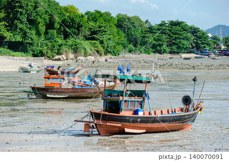 many empty Thai fishing boats lay down on a sea base next to the beach that run out of seawater during low tide 140070091