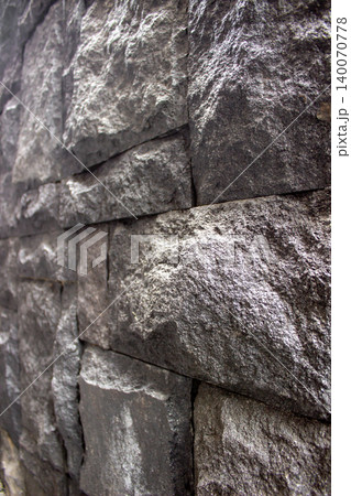 Dark black andesite stone wall texture with rectangular cuts. Dark black andesite stone wall texture with rectangular cuts. 140070778