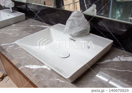 White Kohler ceramic basin sink installed on dark gray countertop. White Kohler ceramic basin sink installed on dark gray countertop. 140070820