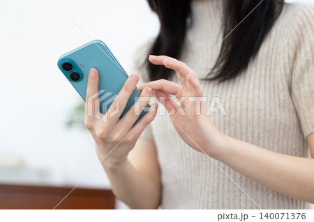 スマホを見ている女性の手元 140071376