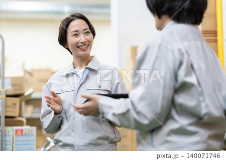 倉庫で打ち合わせをするミドルの女性 倉庫で打ち合わせをするミドルの女性 140071746