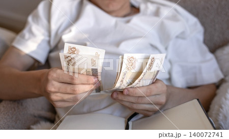 A close up of a man counting 200 polish zloty banknotes while calculating business expenses, loan payments or domestic taxes in a notebook. 140072741