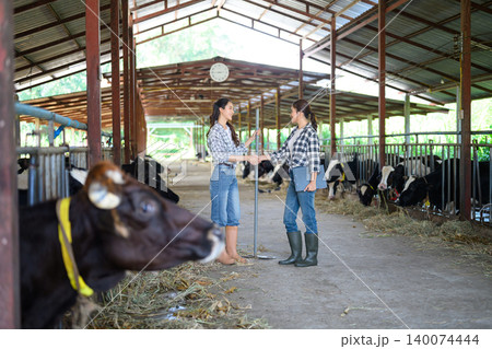 Female farmers shaking hands in dairy barn teamwork agreement 140074444