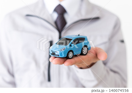 自動車の模型を持つグレーの作業着姿のミドル男性ビジネスマン白バック 140074556