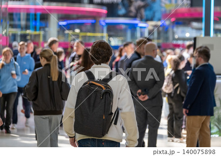Young person with backpack walking through busy indoor crowd of commuters and shoppers at city center 140075898