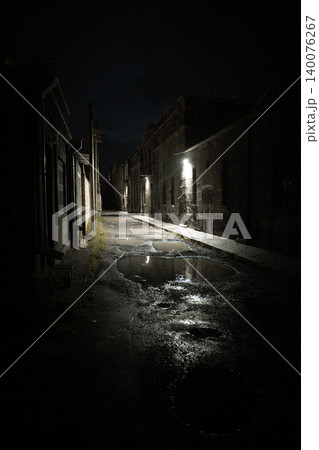 Night scene of empty urban alley with puddles reflecting lights Night scene of empty urban alley with puddles reflecting lights 140076267