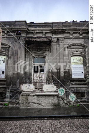 Decaying historic facade with graffiti, moss, and broken windows on rainy day 140076284