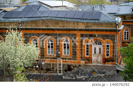 Rainy day view of an old stone building with arched windows and trees Rainy day view of an old stone building with arched windows and trees 140076292
