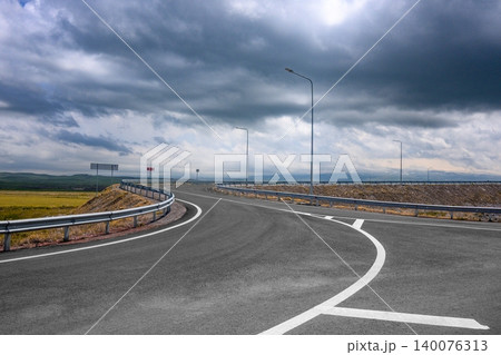 Winding highway under heavy clouds with no visible wildlife or vegetation Winding highway under heavy clouds with no visible wildlife or vegetation 140076313