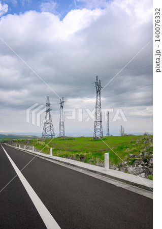 Asphalt road stretches toward horizon with power towers 140076332