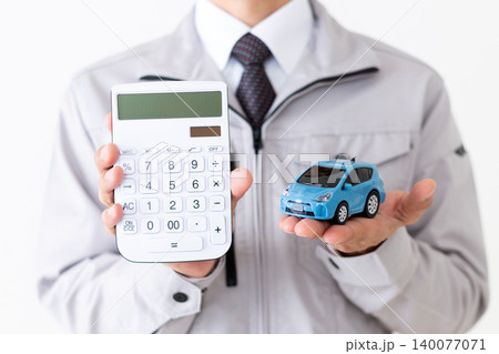 自動車の模型と電卓を持つグレーの作業着姿のミドル男性ビジネスマン白バック 自動車の模型と電卓を持つグレーの作業着姿のミドル男性ビジネスマン白バック 140077071