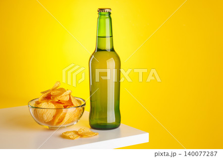 Beer bottle and chips on yellow background snack setup Beer bottle and chips on yellow background snack setup 140077287