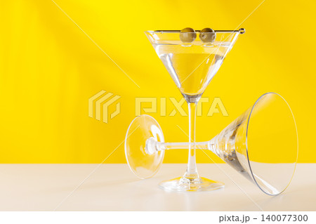 Classic martini cocktail with olives in glass on yellow background 140077300