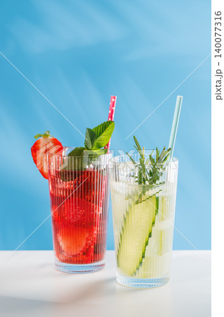 Colorful non alcoholic summer drinks with strawberry and cucumber on blue background Colorful non alcoholic summer drinks with strawberry and cucumber on blue background 140077316
