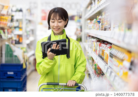 オンラインネットスーパー　商品をピックアップする女性スタッフ 140077378