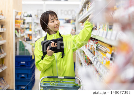 オンラインネットスーパー　商品をピックアップする女性スタッフ 140077395