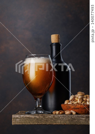 Beer glass with foam and bottle with pistachios Beer glass with foam and bottle with pistachios 140077493