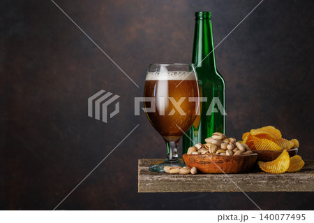 Beer glass with foam and bottle with pistachios 140077495