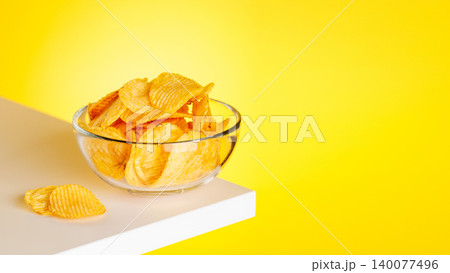 Bowl of potato chips on yellow background minimal snack composition 140077496