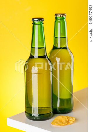 Green glass beer bottles on yellow background minimal studio composition Green glass beer bottles on yellow background minimal studio composition 140077498