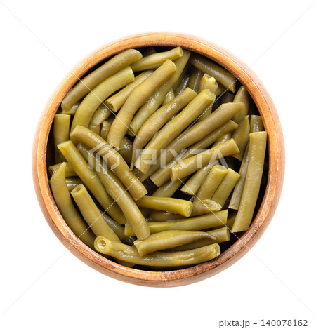 Canned cut green beans in a wooden bowl. Young green bean pods, sliced crosswise into uniform pieces, pressure-cooked and sealed in water-based canning. Isolated close-up from above, over white. Photo Canned cut green beans in a wooden bowl. Young green bean pods, sliced crosswise into uniform pieces, pressure-cooked and sealed in water-based canning. Isolated close-up from above, over white. Photo 140078162